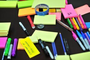 Colorful assortment of office supplies on a desk, including sticky notes, pens, and markers.